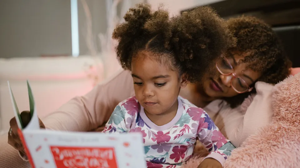 Mother and daughter reading a picture book together at home.