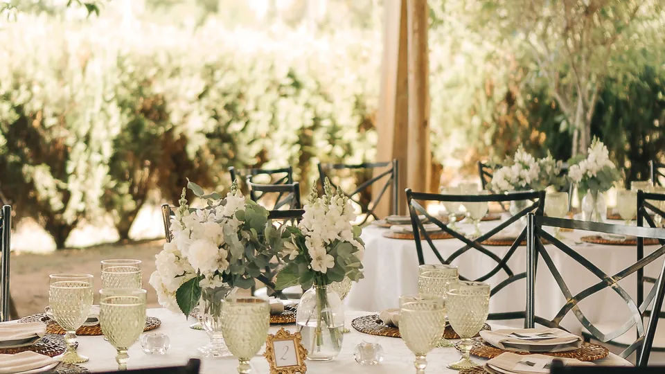 An outdoor wedding reception table decorated with flowers and greenery.
